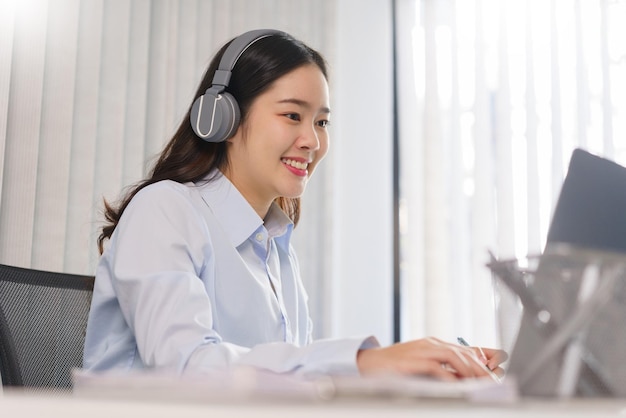 Concetto di business Donna d'affari in cuffia per incontrarsi in videoconferenza e prendere appunti su carta