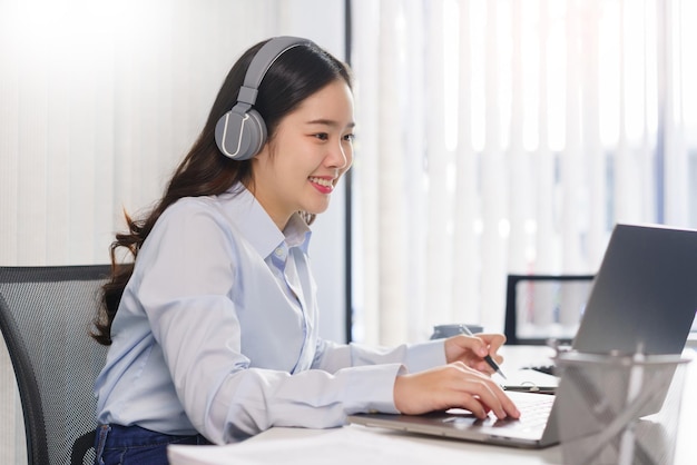 Concetto di business Donna d'affari in cuffia per incontrarsi in videoconferenza e prendere appunti su carta