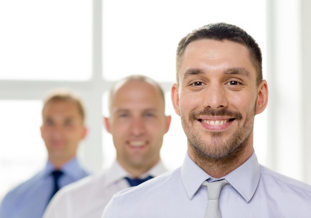 concetto di business e ufficio - uomo d'affari sorridente in ufficio con la squadra sul retro