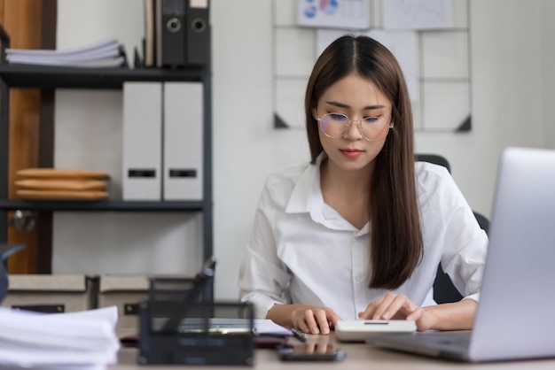 Concetto di business Imprenditrice leggendo il documento e utilizzare la calcolatrice per calcolare il budget di investimento