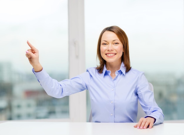 concetto di business, istruzione e tecnologia - donna sorridente che punta a qualcosa o premendo il pulsante immaginario