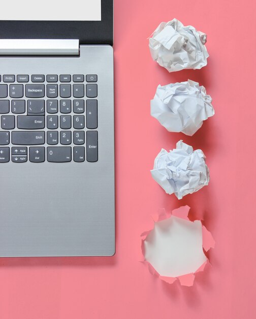 Concetto di business minimalista. Notebook, palline di carta stropicciata, in rosa con un buco strappato