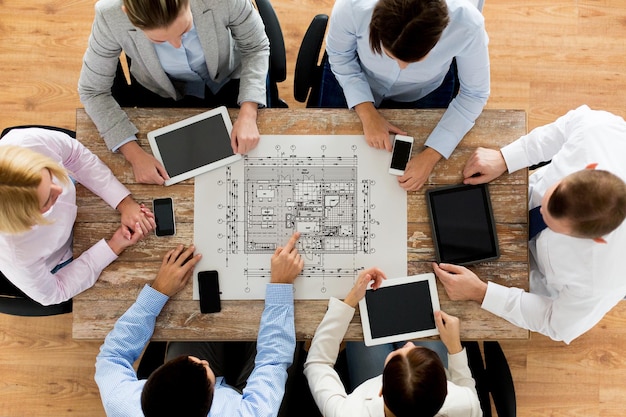 concetto di business, persone, architettura e lavoro di squadra - primo piano del team di architetti con blueprint, smartphone e tablet pc seduti al tavolo in ufficio