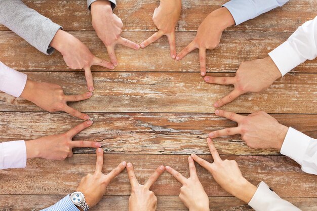 concetto di business, persone, gesto e lavoro di squadra - primo piano del team creativo che mostra il segno della mano di vittoria sul tavolo in ufficio