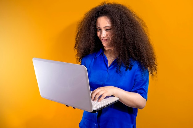 Concetto di business Ritratto di donna felice in seduta casual e tenendo il laptop isolato su sfondo arancione