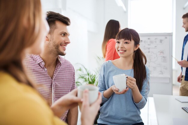 concetto di business, startup e persone - felice team creativo o studenti che bevono caffè e parlano in ufficio