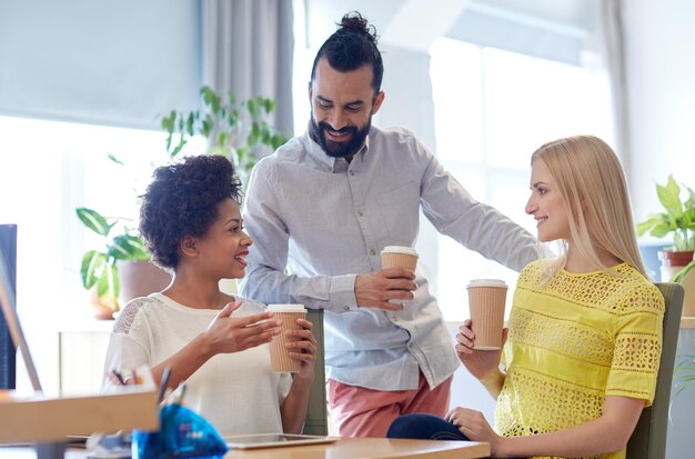 concetto di business, startup, persone e lavoro di squadra - felice team creativo che beve caffè in ufficio