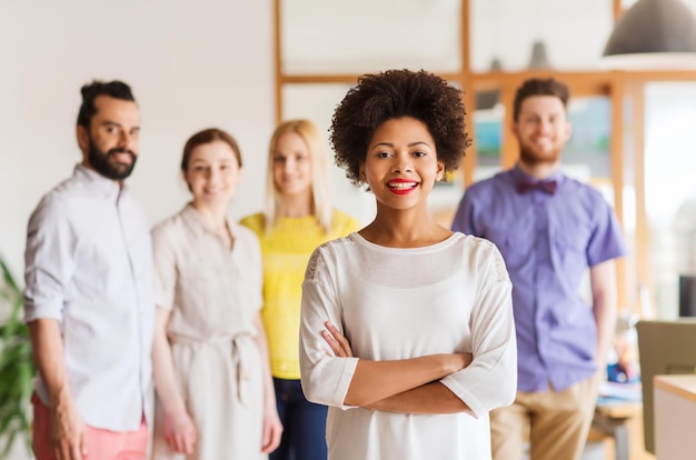 concetto di business, startup, persone e lavoro di squadra - giovane donna africana felice sopra il team creativo internazionale in ufficio