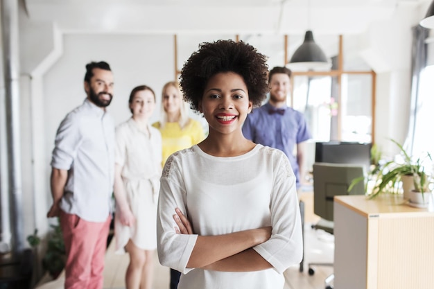 concetto di business, startup, persone e lavoro di squadra - giovane donna felice nel team creativo in ufficio