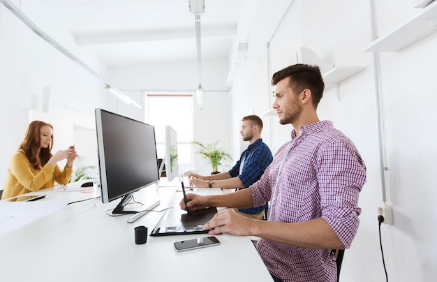 concetto di business, tecnologia, design e persone - giovane creativo o designer con computer e pen tablet che lavora in ufficio