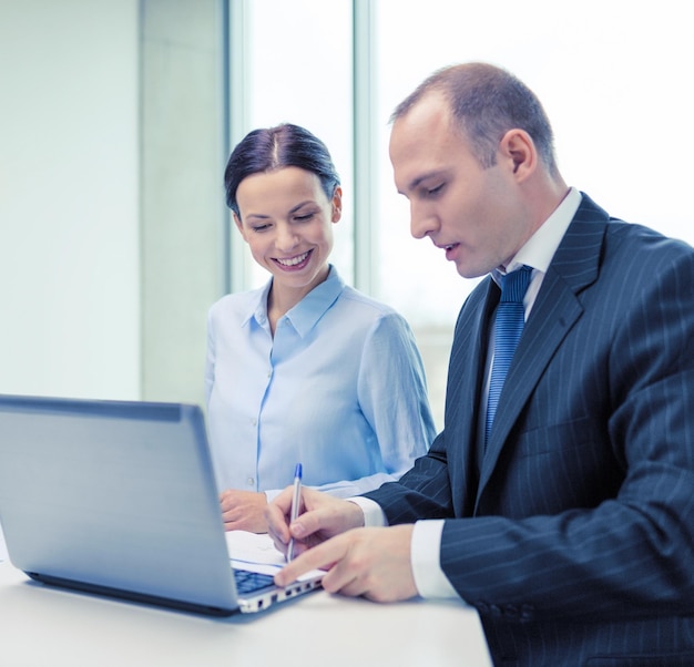 concetto di business, tecnologia e ufficio - sorridente team aziendale con computer portatile e documenti che hanno discussione in ufficio