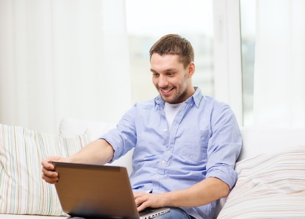 concetto di business, tecnologia ed e-learning - uomo sorridente che lavora con il laptop a casa