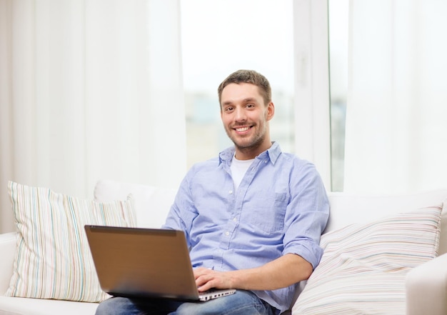 concetto di business, tecnologia ed e-learning - uomo sorridente che lavora con il laptop a casa