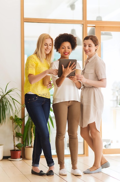 concetto di business, tecnologia, persone e lavoro di squadra - felice team creativo internazionale di tre donne con computer tablet pc e caffè in ufficio