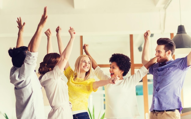 concetto di business, trionfo, gesto, persone e lavoro di squadra - felice team creativo internazionale che alza le mani e celebra la vittoria in carica