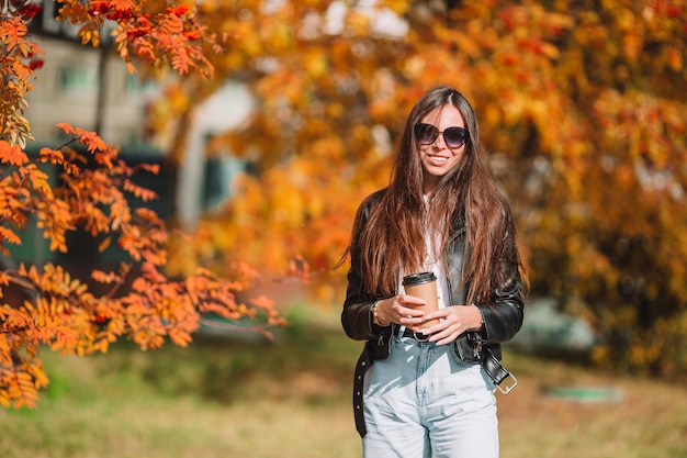 Concetto di caduta - bella donna nel parco di autunno sotto il fogliame di caduta