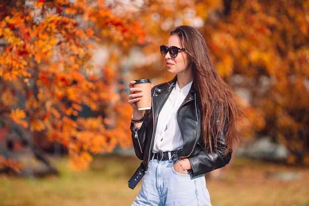 Concetto di caduta - bella donna nel parco di autunno sotto il fogliame di caduta