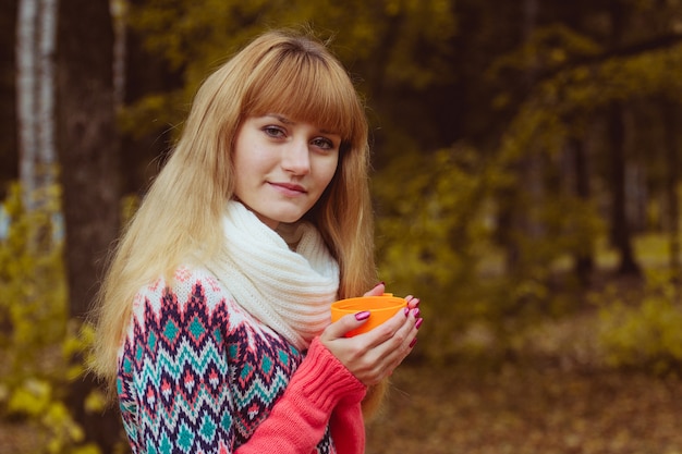 Concetto di caduta - caffè bevente della donna di autunno in parco