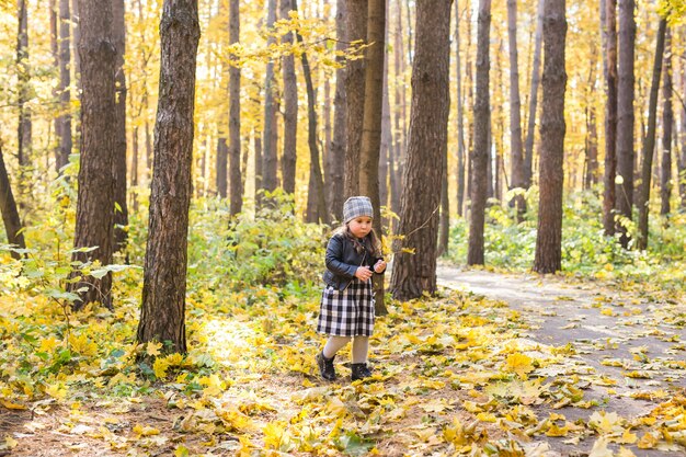 Concetto di caduta, natura e infanzia - piccolo bambino felice che gioca nel parco con foglie gialle.