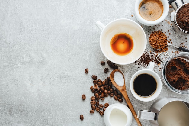 Concetto di caffè con diversi tipi di caffè e oggetti di scena per la preparazione del caffè su sfondo grigio. Vista dall'alto.