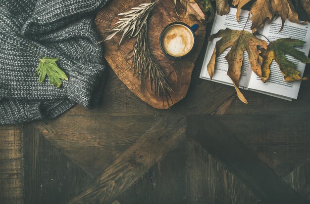 Concetto di caffè mattutino autunnale con jamper di foglie e libro