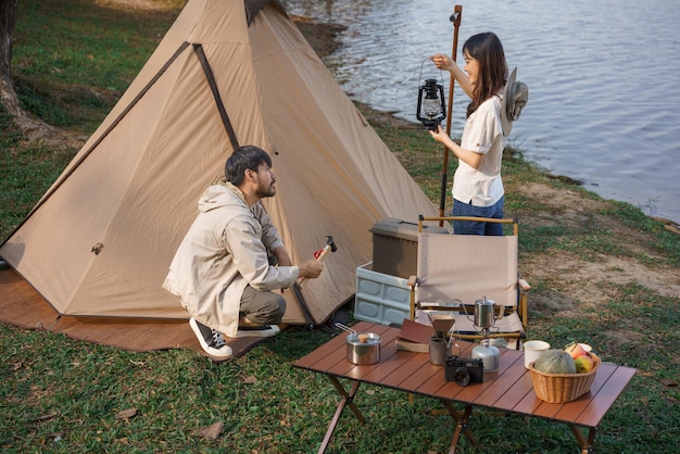Concetto di campeggio e viaggio Coppia giovane zaino in spalla tenda da lancio e lanterna per il campeggio vicino al lago