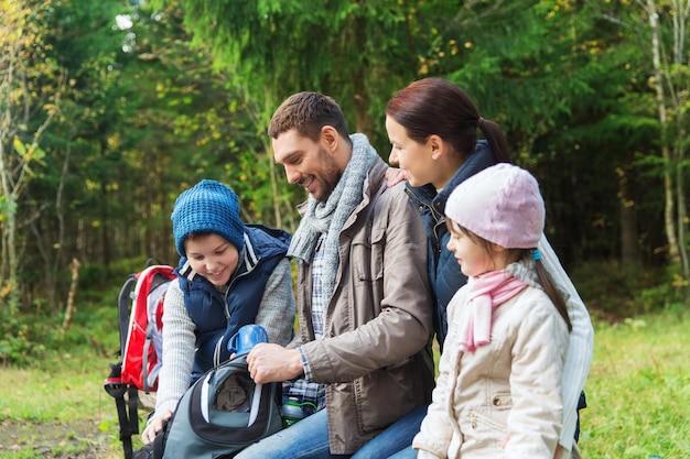 concetto di campeggio, viaggi, turismo, escursione e persone - famiglia felice con zaini e thermos al campo