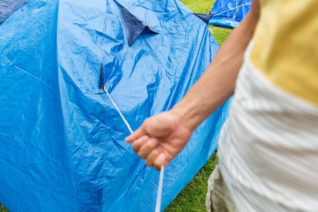 concetto di campeggio, viaggi, turismo, escursione e persone - primo piano dell'uomo che monta una tenda all'aperto