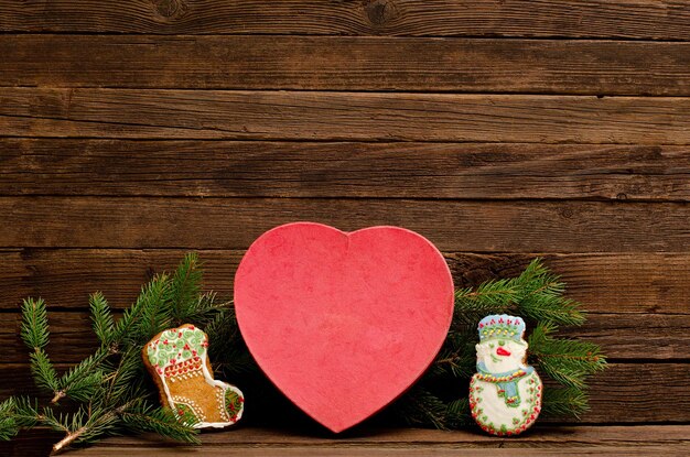 Concetto di Capodanno Biscotti di pan di zenzero a forma di cuore di scatola ramo di abete e pan di zenzero sullo sfondo di legno