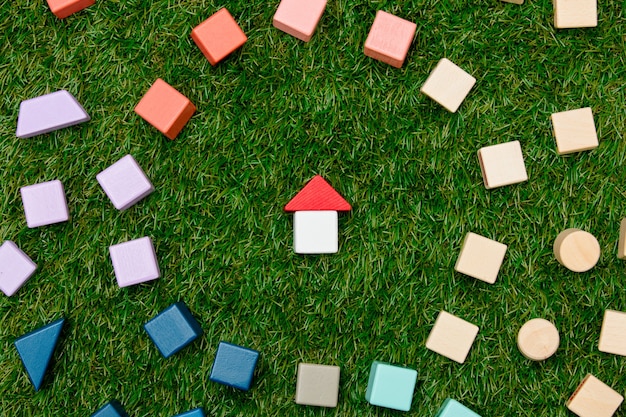 Concetto di casa giocattolo in legno e altri blocchi intorno sull'erba verde.