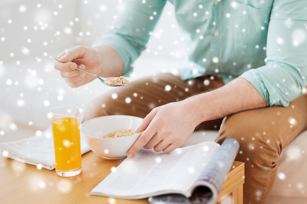 concetto di casa, riposo, notizie, colazione e persone - primo piano di un uomo che legge una rivista e fa colazione a casa