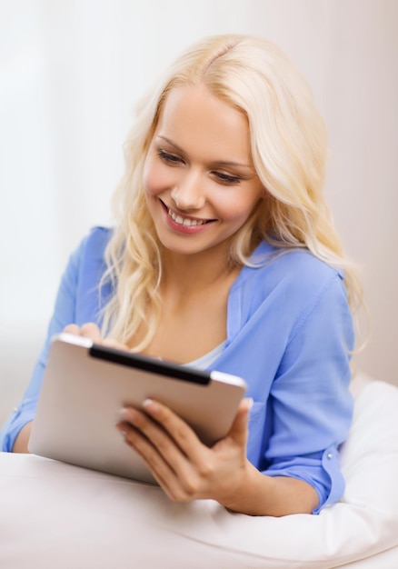 concetto di casa, tecnologia e internet - donna sorridente sdraiata sul divano con computer tablet pc a casa