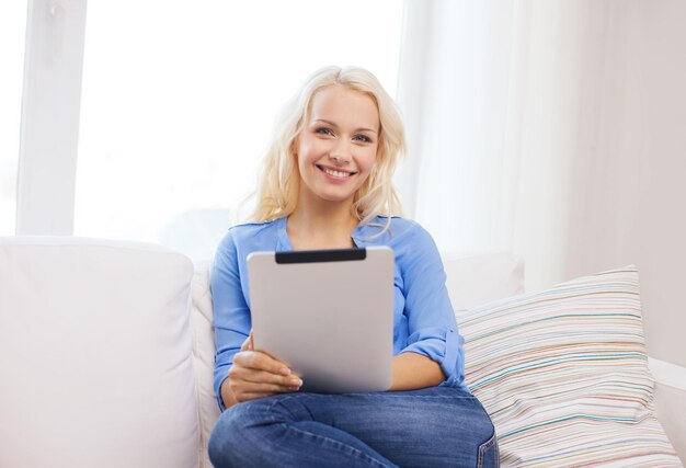 concetto di casa, tecnologia e internet - donna sorridente seduta sul divano con computer tablet pc a casa