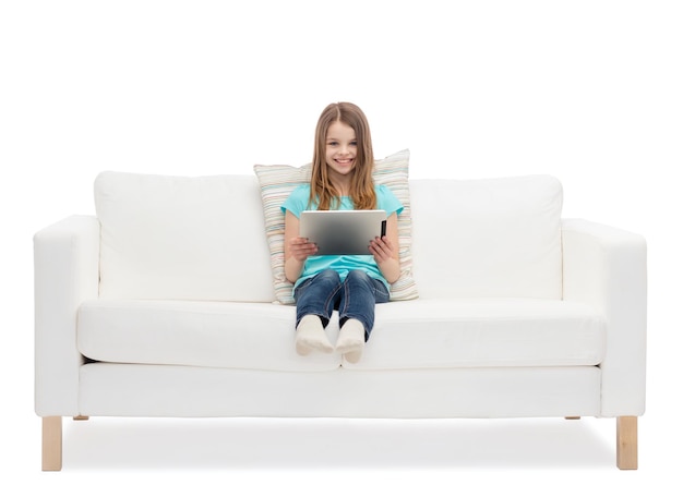 concetto di casa, tempo libero, tecnologia e felicità - bambina sorridente seduta sul divano con computer tablet pc