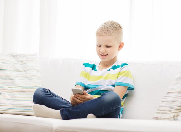 concetto di casa, tempo libero, tecnologia e internet - ragazzino sorridente con smartphone a casa