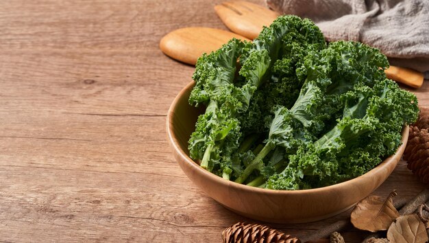 concetto di cavolo fresco lascia insalata in una ciotola su sfondo tavolo in legno.