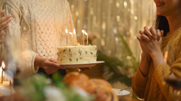 Concetto di celebrazione del compleanno Le ragazze asiatiche esprimono un desiderio mentre ricevono la torta di compleanno dagli amici