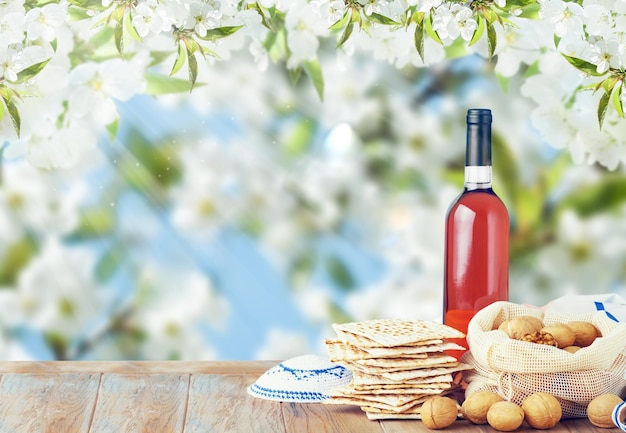 Concetto di celebrazione della Pasqua Matzah rosso kosher e noce su tavolo in legno vintage tavolo di fronte al fiore primaverile giardino di alberi e fiori paesaggio con raggi di sole con spazio di copia Mock up