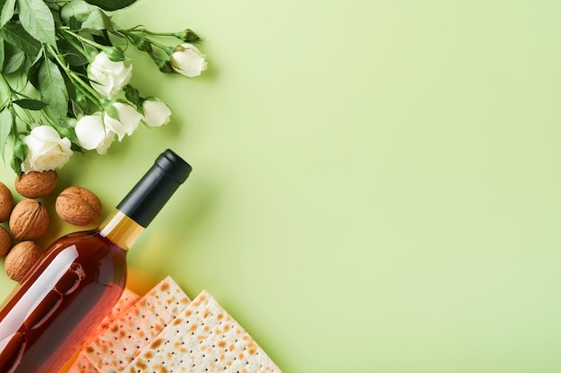 Concetto di celebrazione della pasqua Matzah vino rosso kosher noce e primavera bellissimi fiori di rosa Rituale tradizionale pane ebraico su sfondo verde chiaro Cibo pasquale Festa ebraica di Pesach