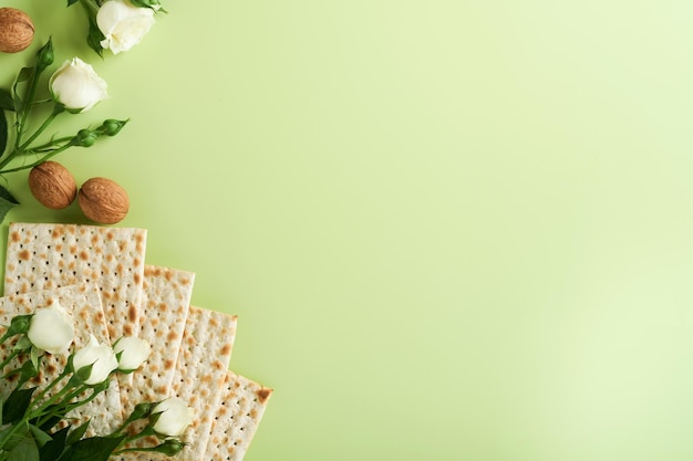 Concetto di celebrazione della pasqua Matzah vino rosso kosher noce e primavera bellissimi fiori di rosa Rituale tradizionale pane ebraico su sfondo verde chiaro Cibo pasquale Festa ebraica di Pesach