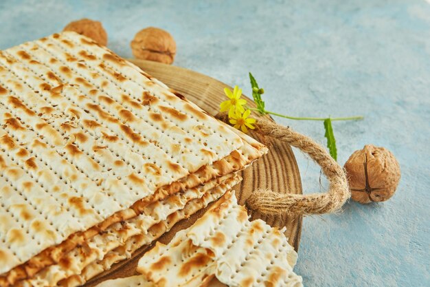 Concetto di celebrazione di Pesach Pasqua ebraica Matzah su supporto in legno con noci e fiori di campo