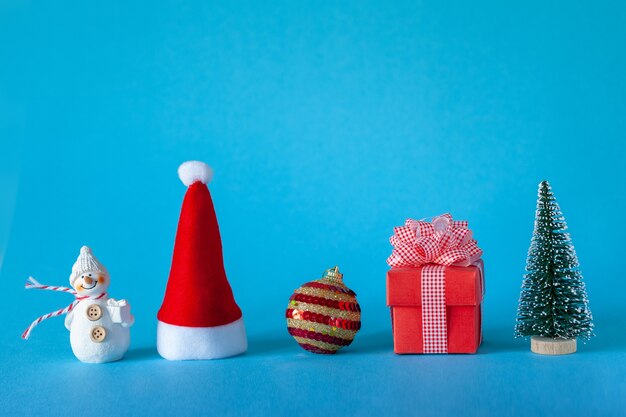 Concetto di celebrazione di vacanze di Natale con albero di Natale e palla, cappello da Babbo Natale, confezione regalo, pupazzo di neve