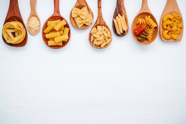 Concetto di cibi italiani e menu design. Vario genere di pasta su fondo di legno bianco.