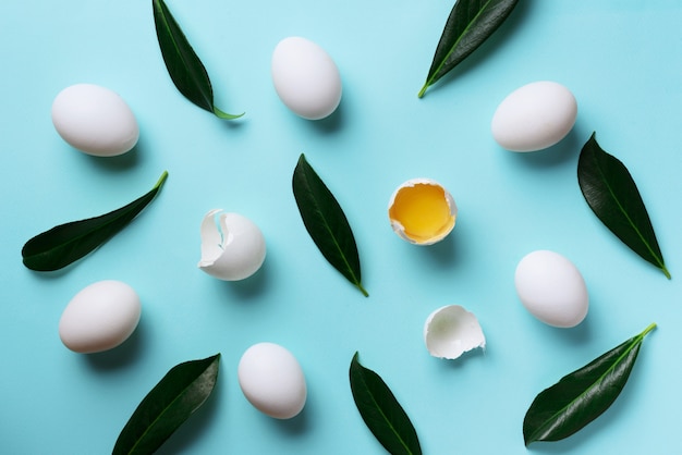 Concetto di cibo con uova bianche, foglie verdi su sfondo di colore blu