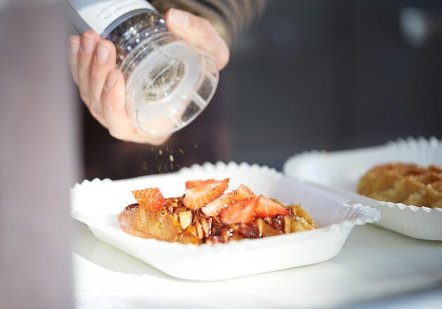 concetto di cibo, cucina, dessert e persone - primo piano della mano del cuoco con waffle alla fragola speziato con spezie mil