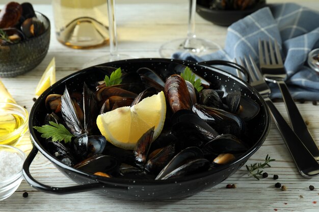 Concetto di cibo delizioso con cozze su un tavolo di legno bianco