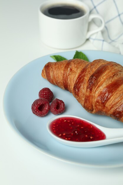 Concetto di cibo delizioso con croissant con marmellata di lamponi su sfondo bianco