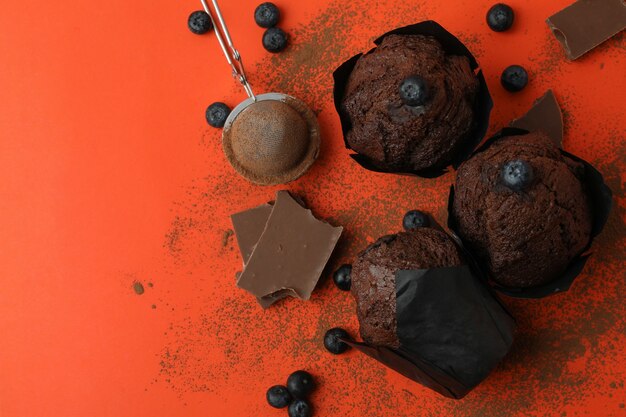 Concetto di cibo delizioso con muffin al cioccolato su sfondo arancione.