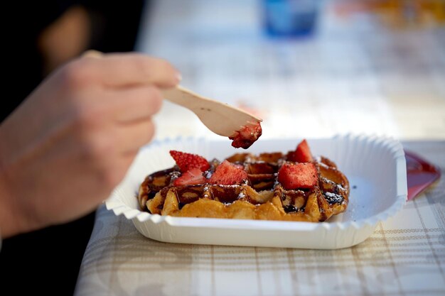 concetto di cibo, dessert e persone - primo piano di una donna che mangia waffle con fragola