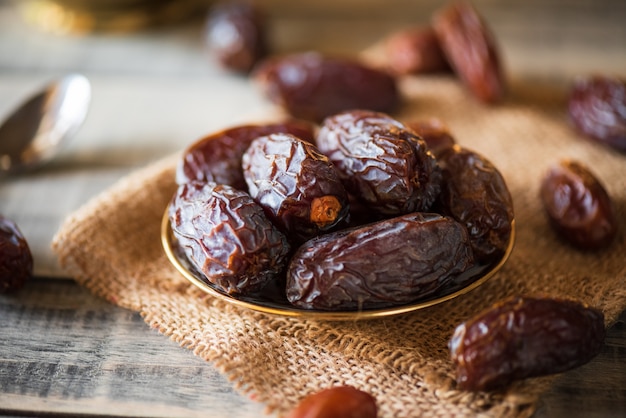 Concetto di cibo e bevande del Ramadan. Le date fruttificano in una ciotola sulla tavola di legno